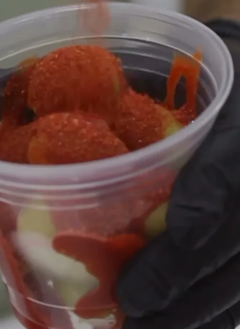 Uvas verdes bañadas en chamoy y cubiertas de chile en polvo, en vaso.