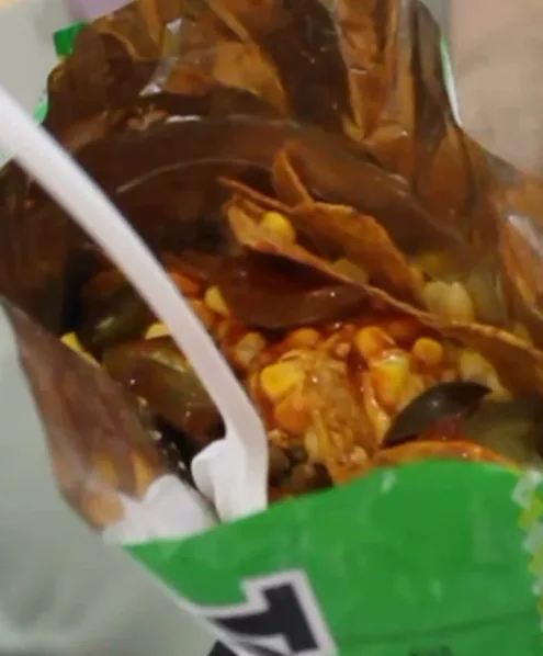 Nachos con queso fundido, granos de elote y rajas de jalapeño, servidos en la bolsa.