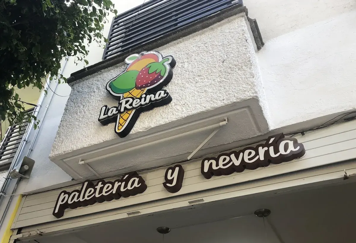 El rótulo de La Reina en relieve sobre la fachada, con el cono de frutas y las letras de paletería y nevería.